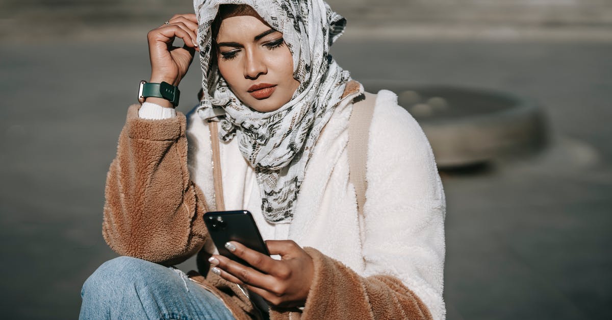 Using Modern Standard Arabic in Arabic-speaking countries - Stylish young ethnic lady in hijab using mobile phone on street Using Modern Standard Arabic in Arabic-speaking countries - Stylish young ethnic lady in hijab using mobile phone on street