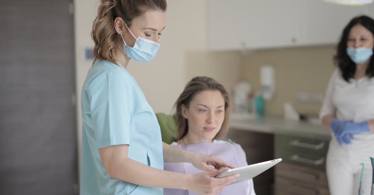 Using my UK Multi Visit visa - Young female dentist using tablet during treatment in clinic Using my UK Multi Visit visa - Young female dentist using tablet during treatment in clinic