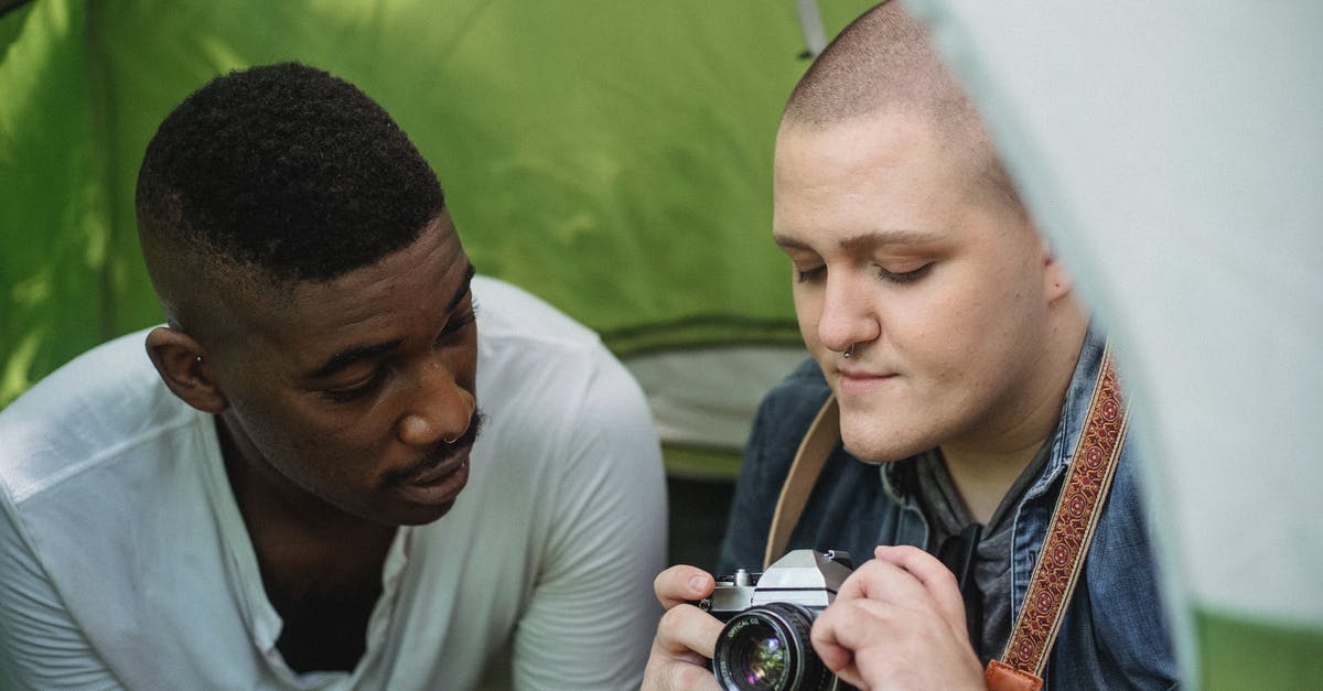 Using old 'full' passport for visa-free travel - Young male showing sharing retro photo camera with African American friend while sitting in green tent Using old 'full' passport for visa-free travel - Young male showing sharing retro photo camera with African American friend while sitting in green tent