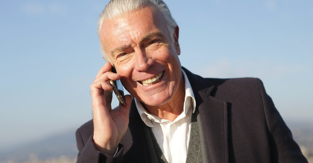 Using old 'full' passport for visa-free travel - Delighted male entrepreneur wearing classy jacket standing in city and making phone call while smiling and looking at camera Using old 'full' passport for visa-free travel - Delighted male entrepreneur wearing classy jacket standing in city and making phone call while smiling and looking at camera