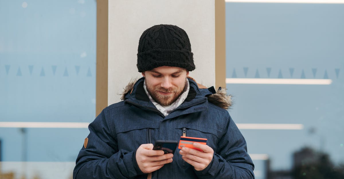 Using one visa-free to enter Vietnam to avoid multiple-entry visa - Cheerful man entering details of credit card on smartphone on street Using one visa-free to enter Vietnam to avoid multiple-entry visa - Cheerful man entering details of credit card on smartphone on street