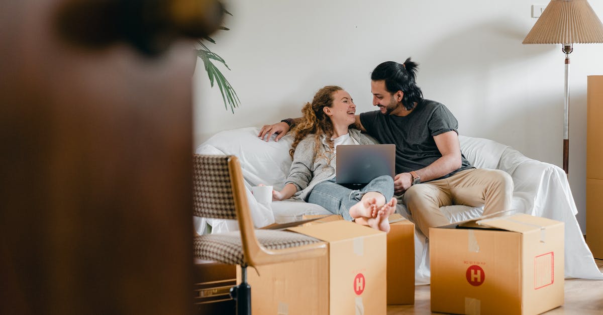 Using parent's property and will as evidence of assets - Cheerful couple in casual clothes sitting on comfortable sofa with laptop and looking at each other while moving to new apartment Using parent's property and will as evidence of assets - Cheerful couple in casual clothes sitting on comfortable sofa with laptop and looking at each other while moving to new apartment