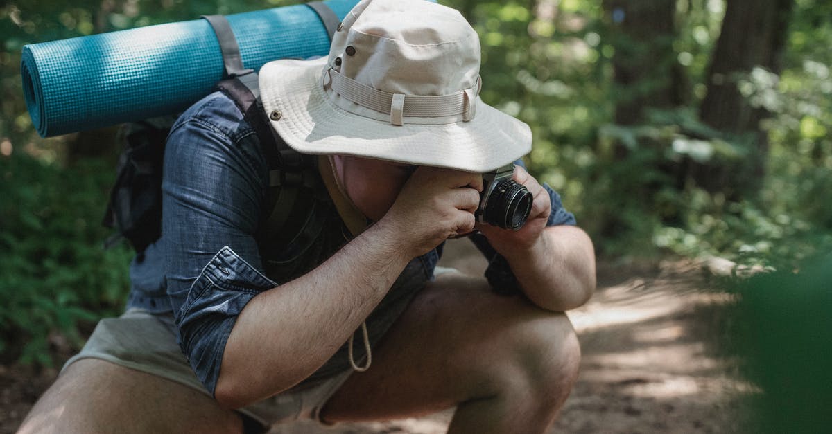 Using squat toilets with arthritic knees - Unrecognizable male tourist with hiking equipment squatting on path while taking photo on camera in summer woods Using squat toilets with arthritic knees - Unrecognizable male tourist with hiking equipment squatting on path while taking photo on camera in summer woods