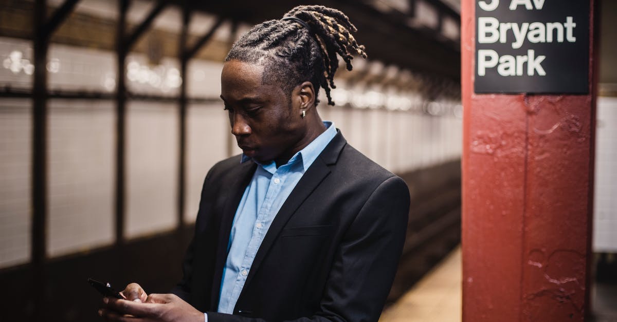 Using the Vatican City train station? - Serious young man using smartphone while waiting for metro train Using the Vatican City train station? - Serious young man using smartphone while waiting for metro train