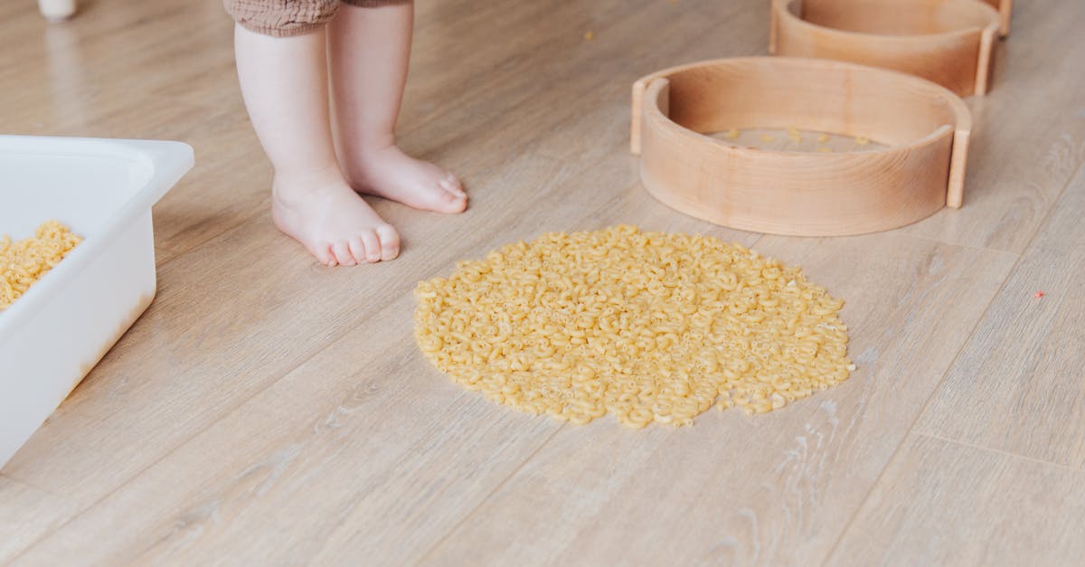 Vancouver YVR getting to quarantine with toddler - Crop faceless toddler standing barefoot on floor and playing with round wooden shapes of different size and pasta developing fine motor skills at home Vancouver YVR getting to quarantine with toddler - Crop faceless toddler standing barefoot on floor and playing with round wooden shapes of different size and pasta developing fine motor skills at home