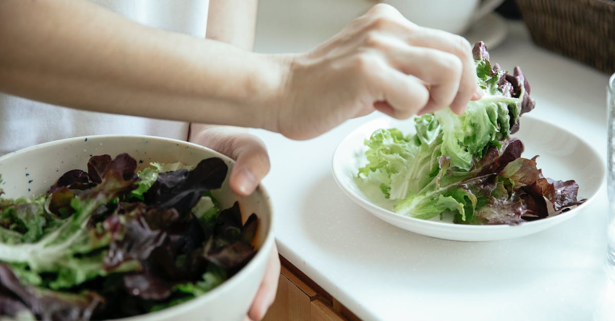 Vegetarian dishes on Russian trains (European part) - From above of crop person putting fresh mix of green salad leaves from bowl into white plate Vegetarian dishes on Russian trains (European part) - From above of crop person putting fresh mix of green salad leaves from bowl into white plate