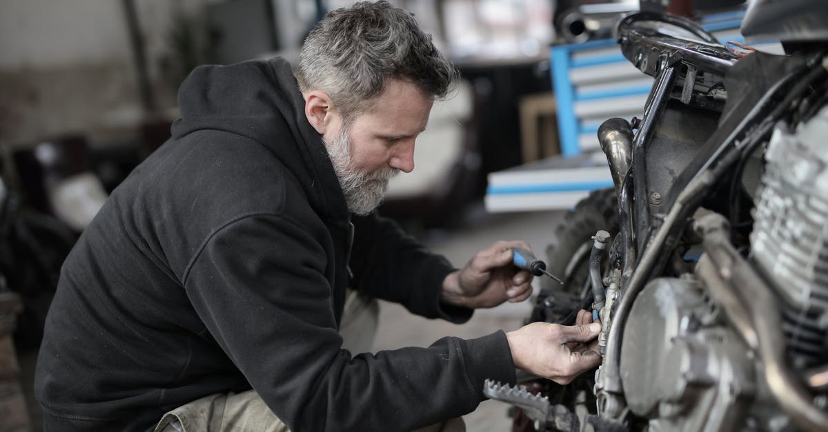 Vehicle Permit at the Mexican Border without owner present - Bearded man fixing motorcycle in workshop Vehicle Permit at the Mexican Border without owner present - Bearded man fixing motorcycle in workshop