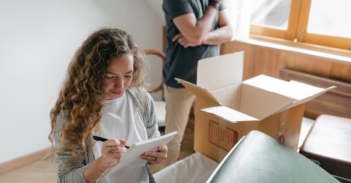Visa requirements for check out and in - Pensive couple taking notes in bedroom near window while packing stuff in carton box to move into new apartment Visa requirements for check out and in - Pensive couple taking notes in bedroom near window while packing stuff in carton box to move into new apartment