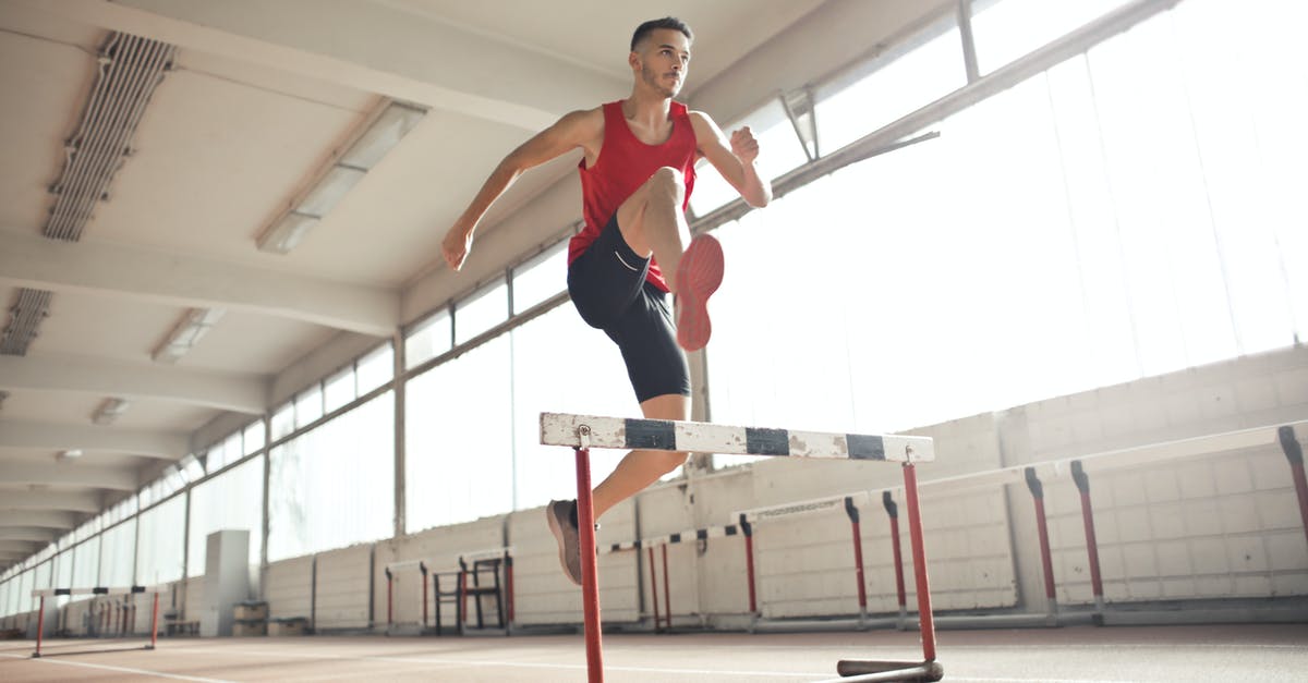 Visa run to Malaysia from Thailand - Powerful male athlete jumping over hurdle on running track while training at sports hall Visa run to Malaysia from Thailand - Powerful male athlete jumping over hurdle on running track while training at sports hall