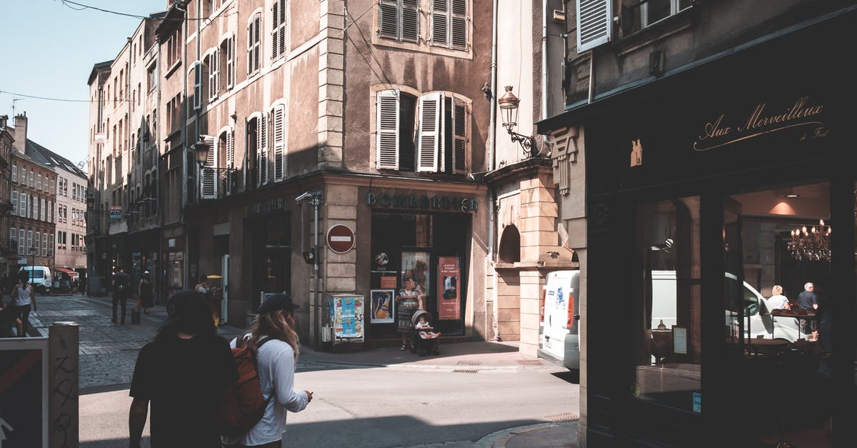 Visa-free visit and re-entry to the UK - Back view of anonymous travelers with backpack strolling on paved walkway between aged buildings with stores on street in shadow Visa-free visit and re-entry to the UK - Back view of anonymous travelers with backpack strolling on paved walkway between aged buildings with stores on street in shadow