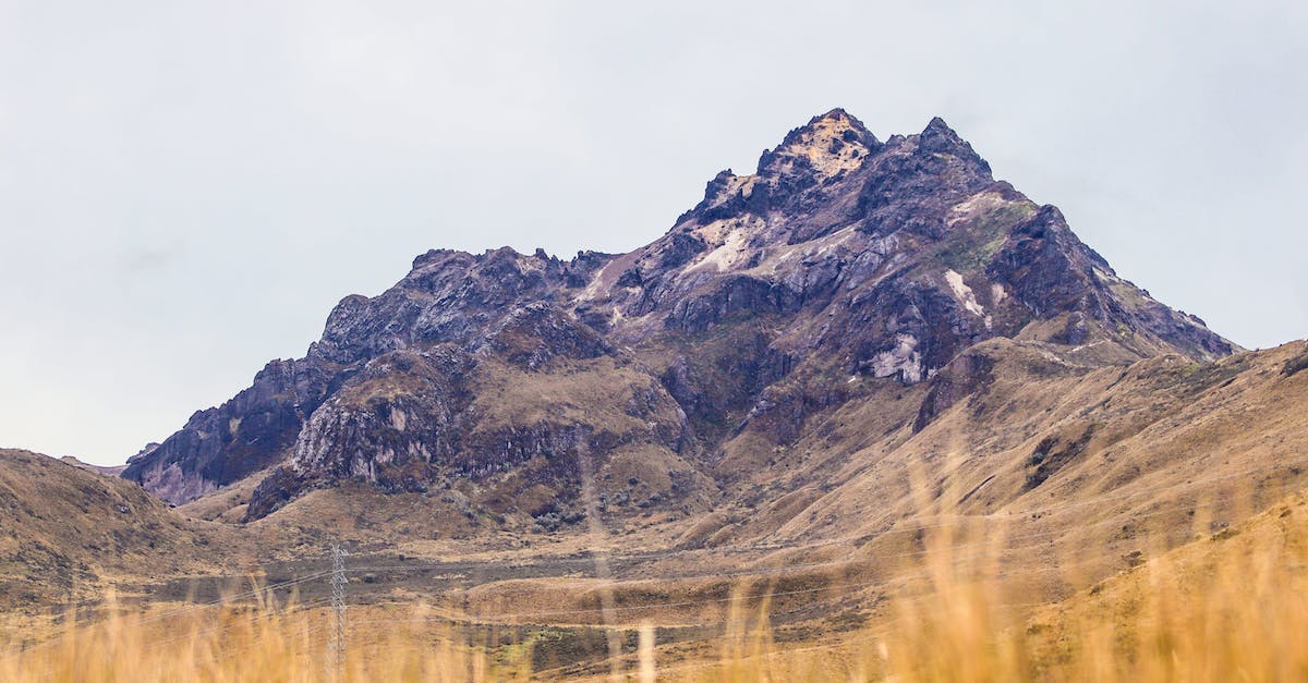 Visit a volcano in Ecuador - Brown Grass Field Near Mountain Under White Sky Visit a volcano in Ecuador - Brown Grass Field Near Mountain Under White Sky