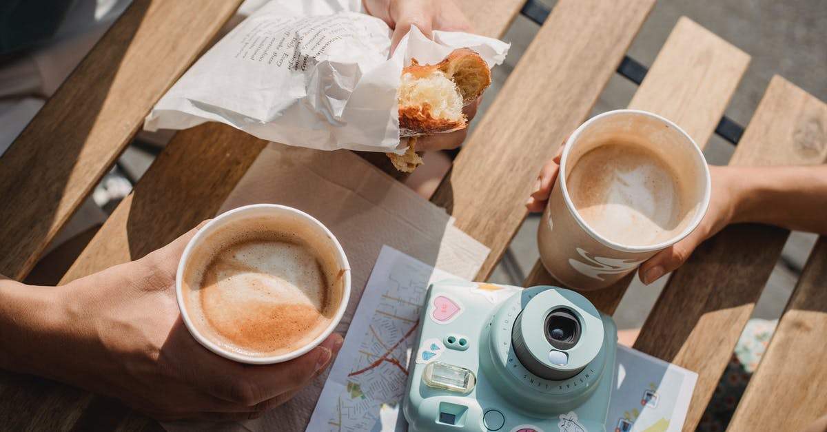Visiting Canada from Europe, with weekend trip to the US – will we need testing when going back to Canada? - From above of crop anonymous couple with disposable glasses of cappuccino and photo camera on table in street cafeteria