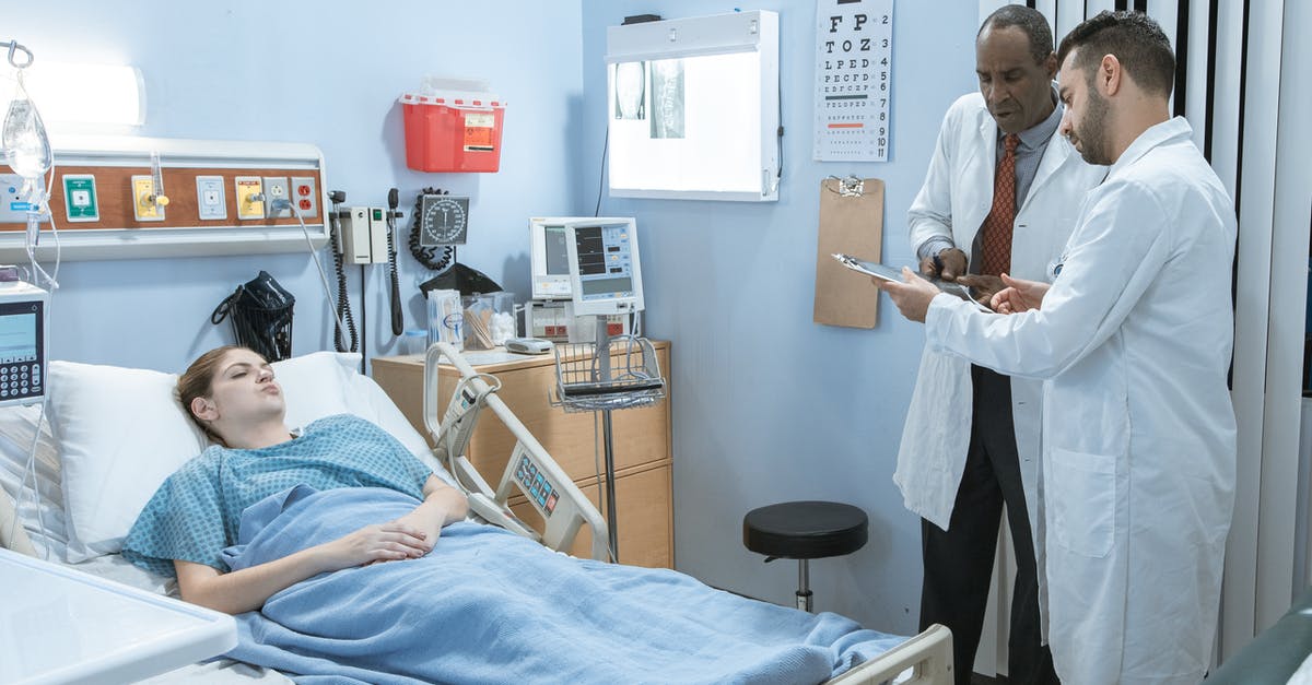 Visiting doctors while staying in Australia? - Man in Blue Scrub Suit Sitting on Hospital Bed Visiting doctors while staying in Australia? - Man in Blue Scrub Suit Sitting on Hospital Bed