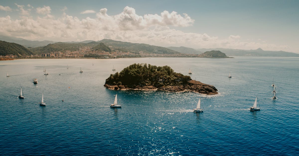 Visiting islands around Cuba - Picturesque seascape of sailboats floating around little island in blue rippling water near hilly coast under cloudy blue sky Visiting islands around Cuba - Picturesque seascape of sailboats floating around little island in blue rippling water near hilly coast under cloudy blue sky