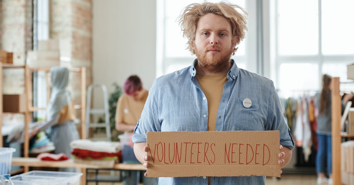Volunteer in UK – which visa needed? - A Man Holding a Cardboard with Inscription Volunteer in UK – which visa needed? - A Man Holding a Cardboard with Inscription