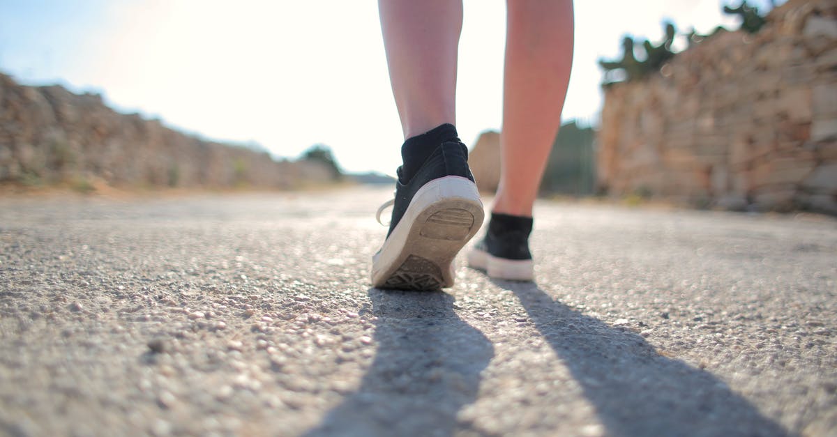 Walking 14 km on a pilgrimage road where footwear may be considered disrespectful - Person in Black Socks and Black Sneakers Walking on Gray Asphalt Road Walking 14 km on a pilgrimage road where footwear may be considered disrespectful - Person in Black Socks and Black Sneakers Walking on Gray Asphalt Road
