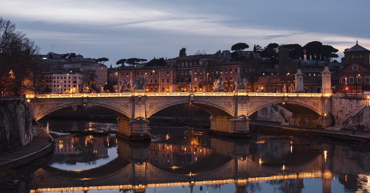 Websites to buy complex air tickets - Aged masonry bridge with arches over Tiber River against urban house facades under cloudy sky in evening Rome Italy Websites to buy complex air tickets - Aged masonry bridge with arches over Tiber River against urban house facades under cloudy sky in evening Rome Italy