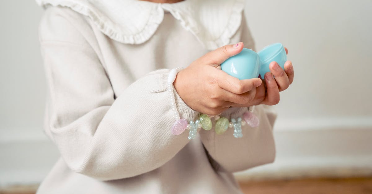 What's open over Easter in Germany? - Crop unrecognizable girl in white dress opening surprise toy egg in light room What's open over Easter in Germany? - Crop unrecognizable girl in white dress opening surprise toy egg in light room
