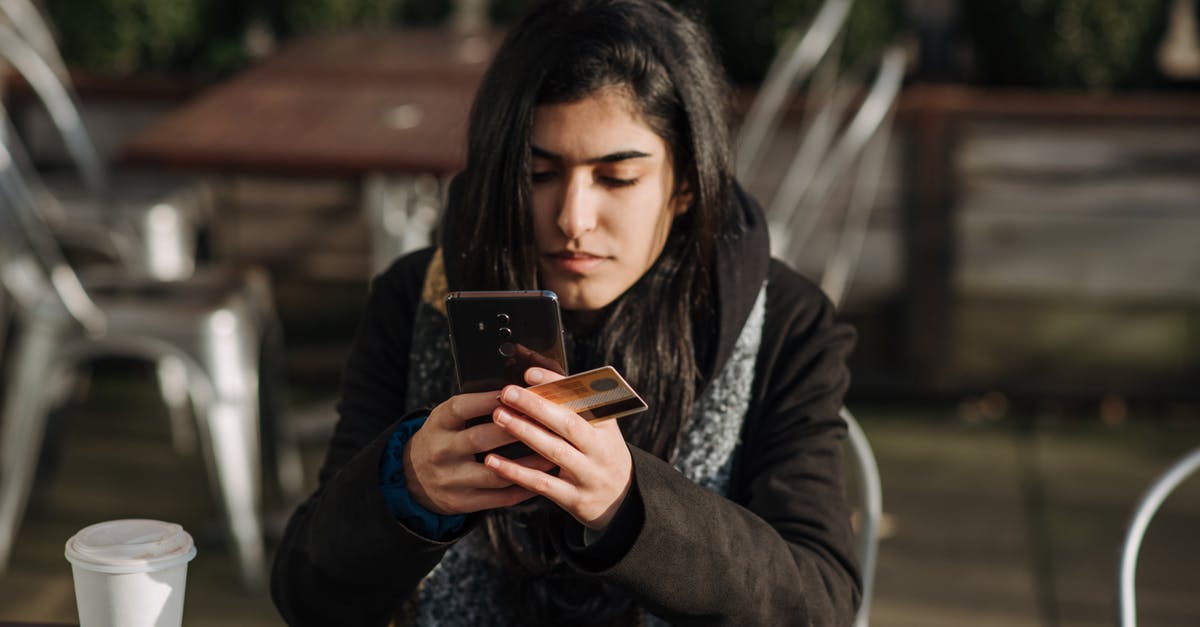 What's the cheapest SIM card with Internet for smartphone in Czech Republic? [duplicate] - Young ethnic female purchaser with credit card shopping online on mobile phone at table with takeaway hot drink in cafeteria