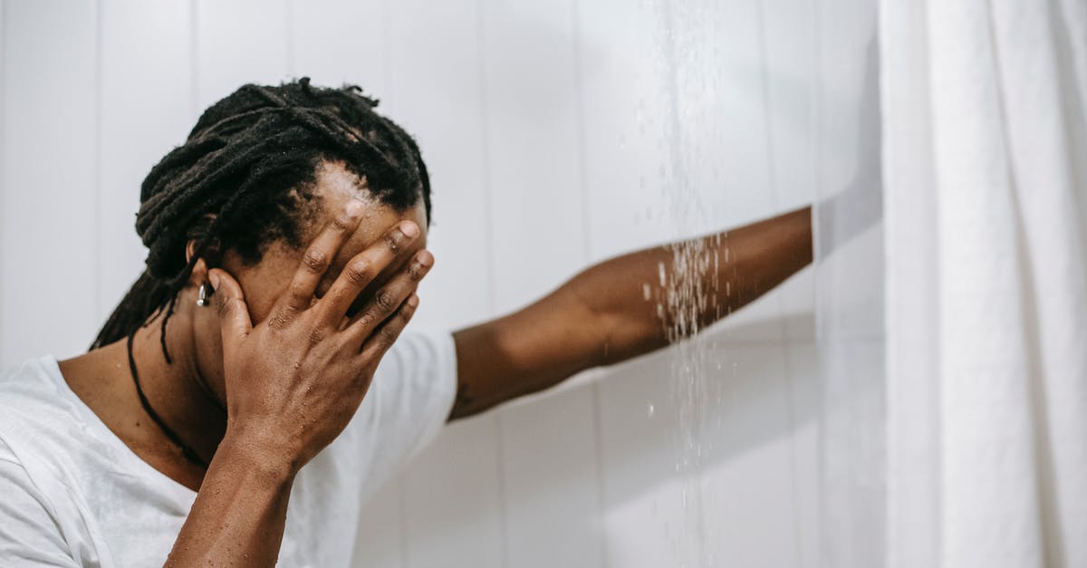 What's the use for this shower drain cover? - Sad African American man covering face with hand in shower cabin What's the use for this shower drain cover? - Sad African American man covering face with hand in shower cabin