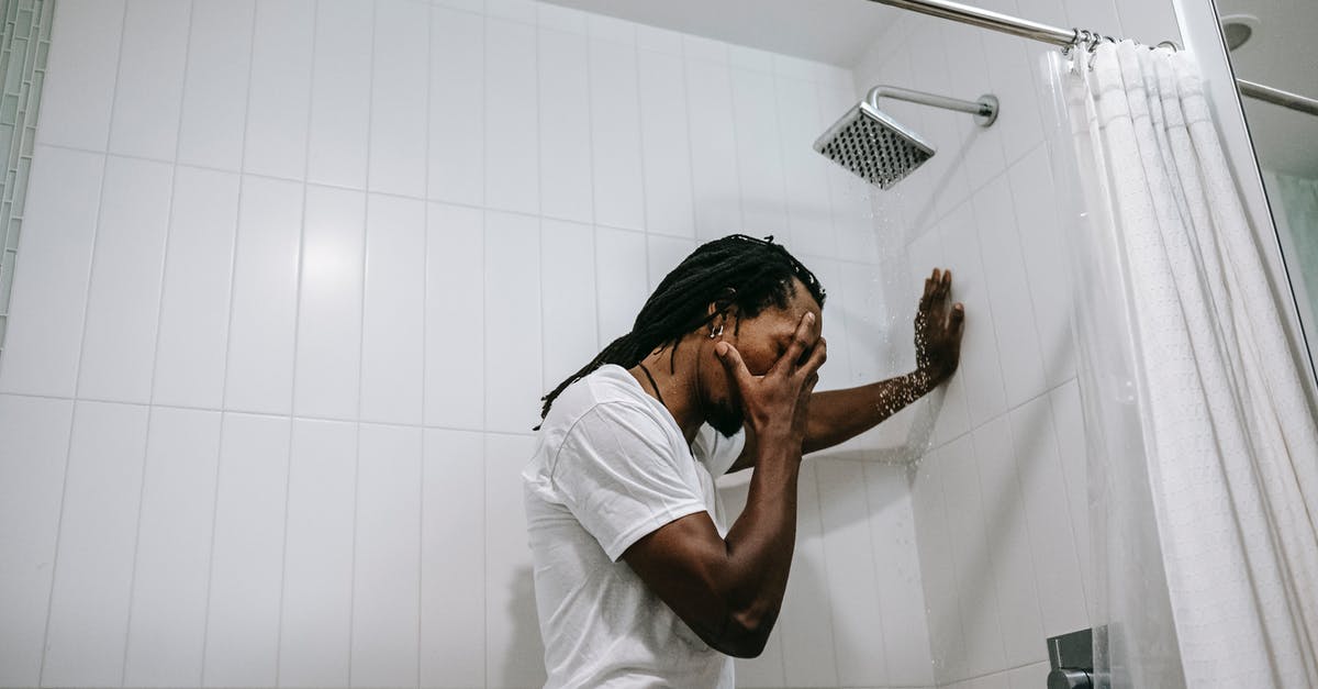 What's the use for this shower drain cover? - Side view depressed preoccupied African American male in white shirt covering face with hand in anxiety in bathroom What's the use for this shower drain cover? - Side view depressed preoccupied African American male in white shirt covering face with hand in anxiety in bathroom