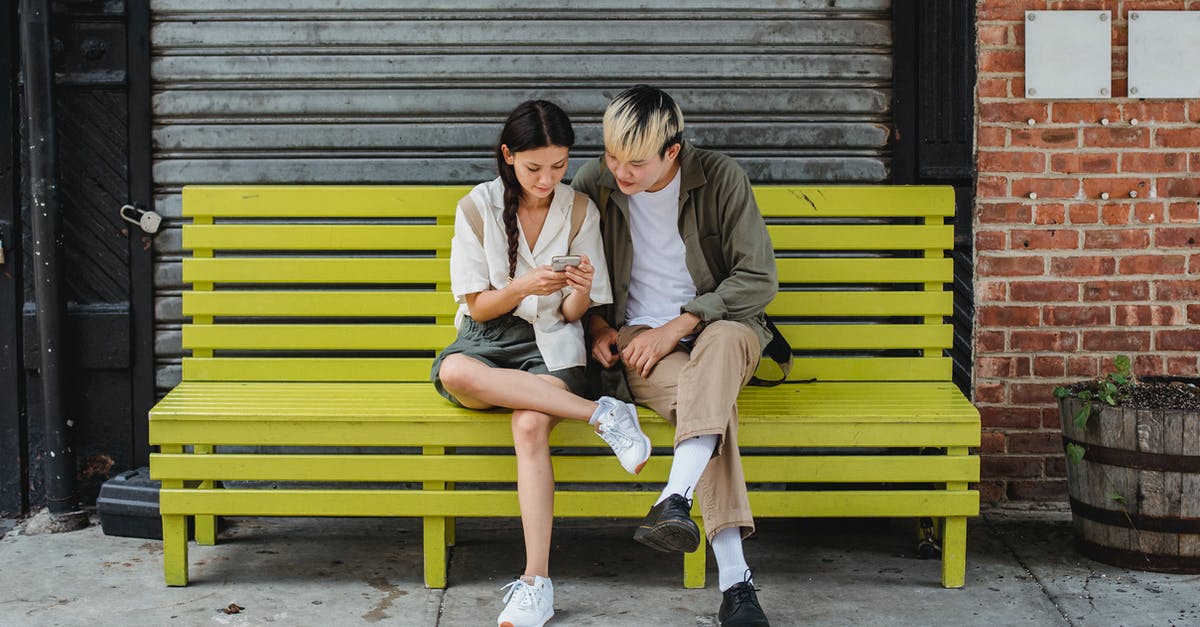 What's the use of trains that spend 6+ hours of daytime en route? [closed] - Serious multiracial couple resting on yellow bench and browsing smartphone and looking at screen