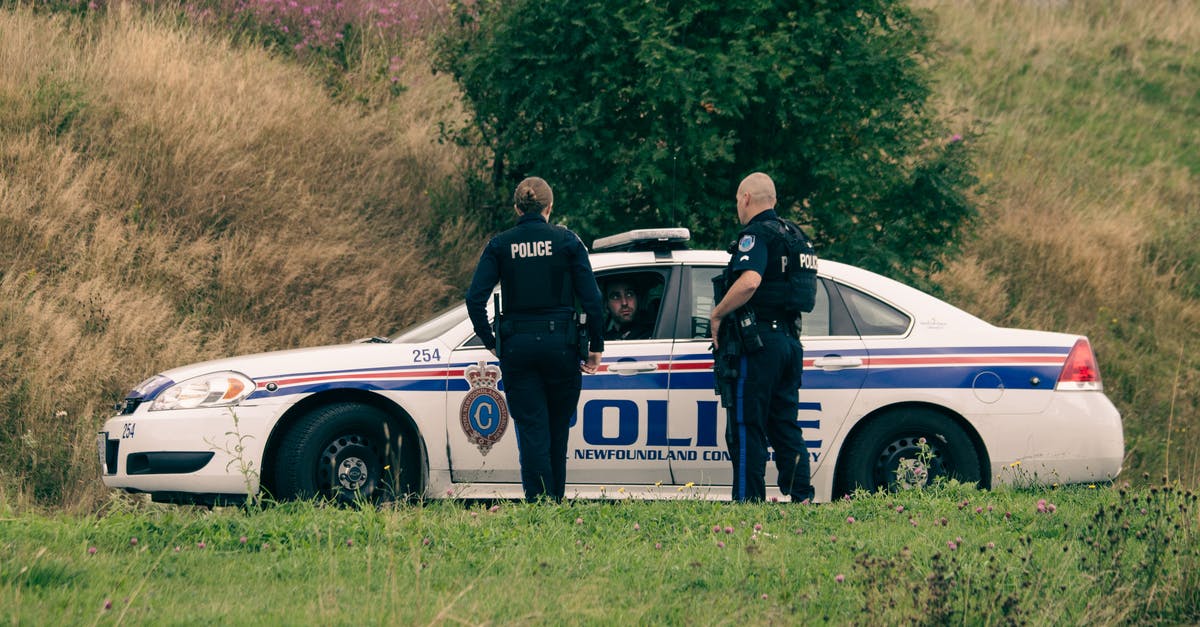 What am I supposed to do if pulled over by a police officer in the US and I can't roll down my car's windows? - Unrecognizable police officers speaking against car on meadow What am I supposed to do if pulled over by a police officer in the US and I can't roll down my car's windows? - Unrecognizable police officers speaking against car on meadow