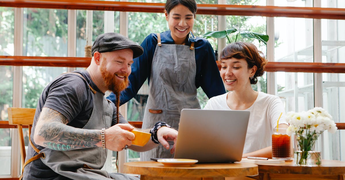 What are some reputable, local operators offering day tours to Machhu Picchu from Cusco [closed] - Positive coworkers in aprons and casual outfit using computer in cafeteria at table with coffee cup and glass of drink in day