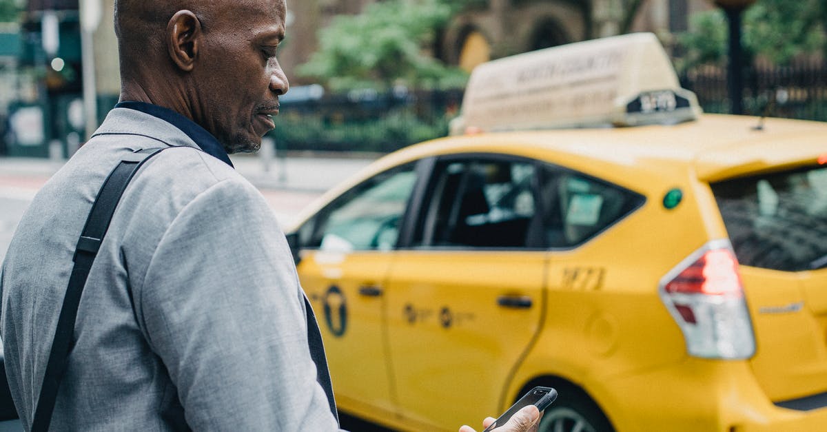 What are these little yellow boxes at German pedestrian crossings? [duplicate] - Busy black businessman checking notification on smartphone while crossing street