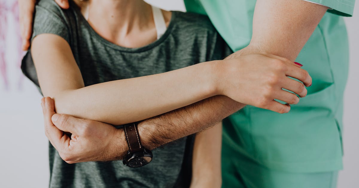 What areas to avoid in Amsterdam for a family-friendly visit - Crop unrecognizable orthopedist stretching shoulder of female patient What areas to avoid in Amsterdam for a family-friendly visit - Crop unrecognizable orthopedist stretching shoulder of female patient