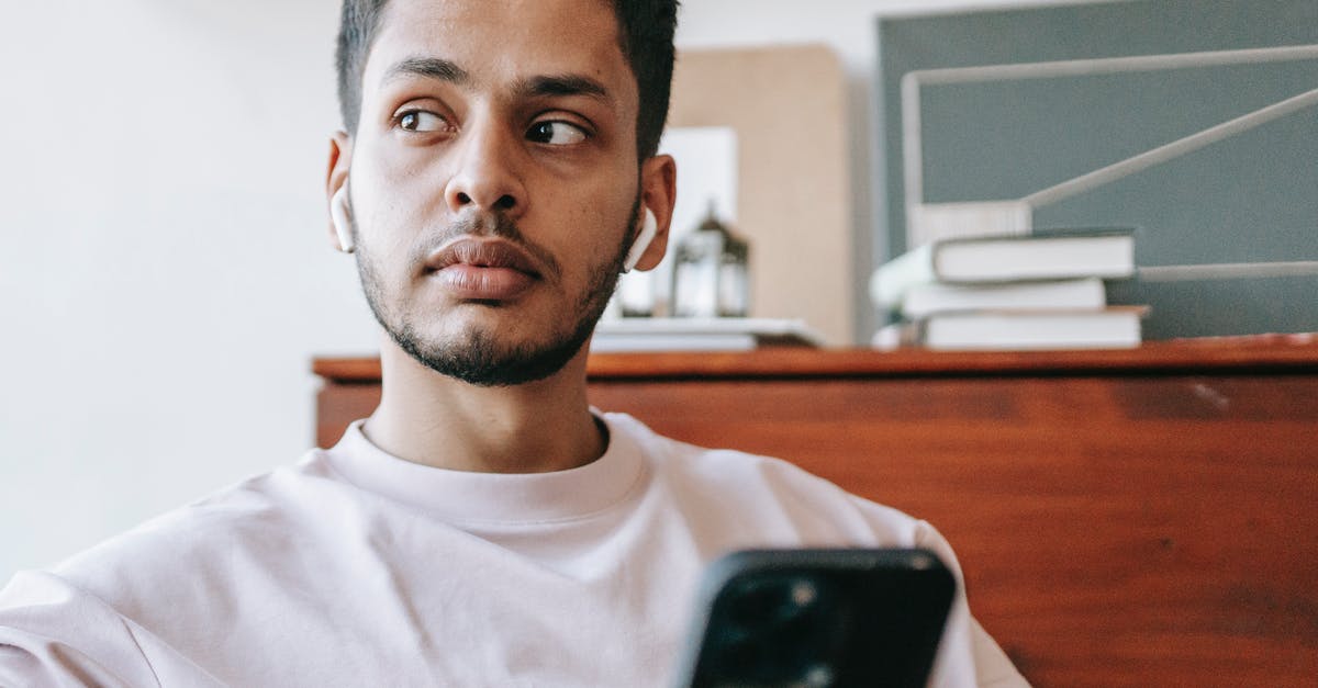 What can I do if a hotel booked online turns me away but keeps my money? - Serious Indian man listening to music in wireless earbuds looking away while texting message on cellphone in light room against table with books What can I do if a hotel booked online turns me away but keeps my money? - Serious Indian man listening to music in wireless earbuds looking away while texting message on cellphone in light room against table with books