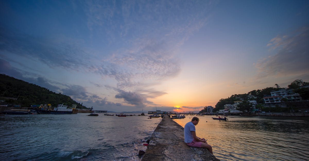 What can I do in Hong Kong with a six-hour layover? - Photo of Man Sitting on Paved Pathway During Golden Hour