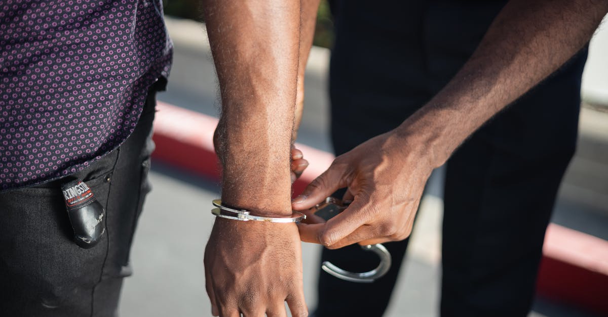 What can security officials do when they suspect my checked baggage? - Police Officer Putting Handcuffs on Another Person
