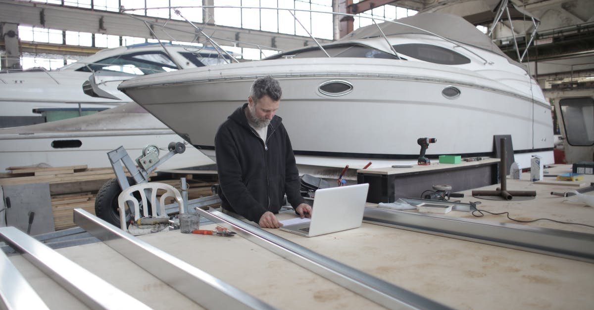 What chemicals does airport security use as markers? - Adult worker using laptop at workbench during work in boat garage