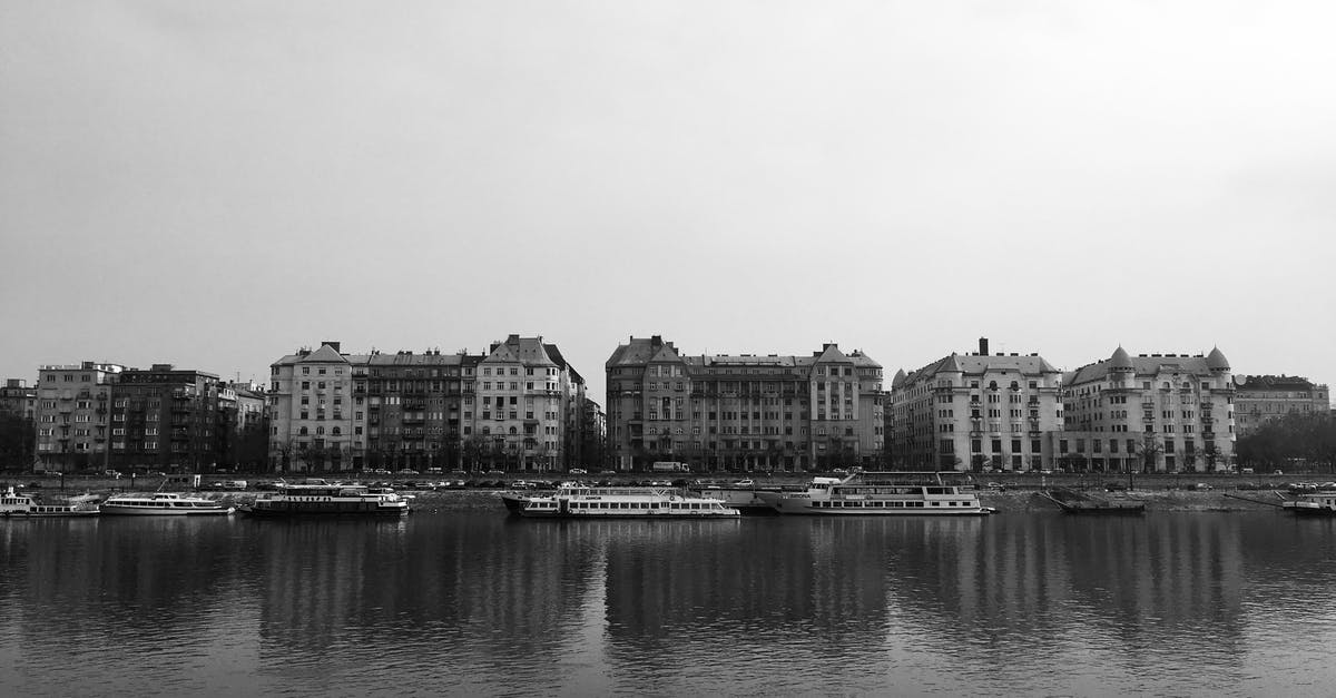 What city are these buildings in? - Grayscale Photo of City Buildings Near Ships on a River What city are these buildings in? - Grayscale Photo of City Buildings Near Ships on a River