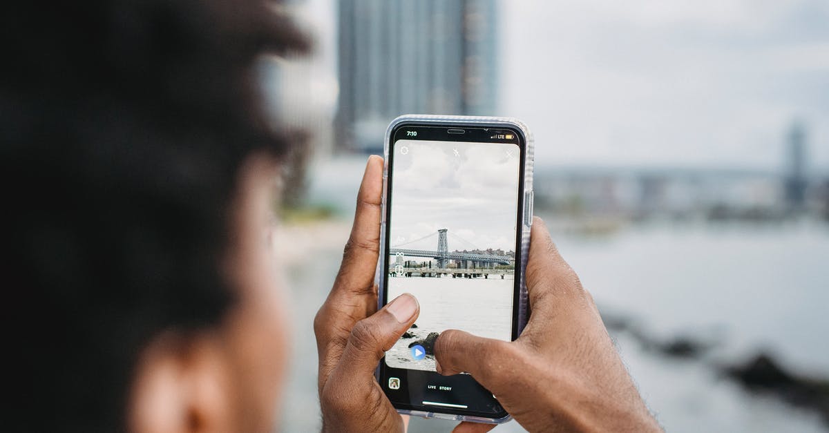What coast or river-adjacent city is in this photo? - Black man taking photo of bridge over river What coast or river-adjacent city is in this photo? - Black man taking photo of bridge over river