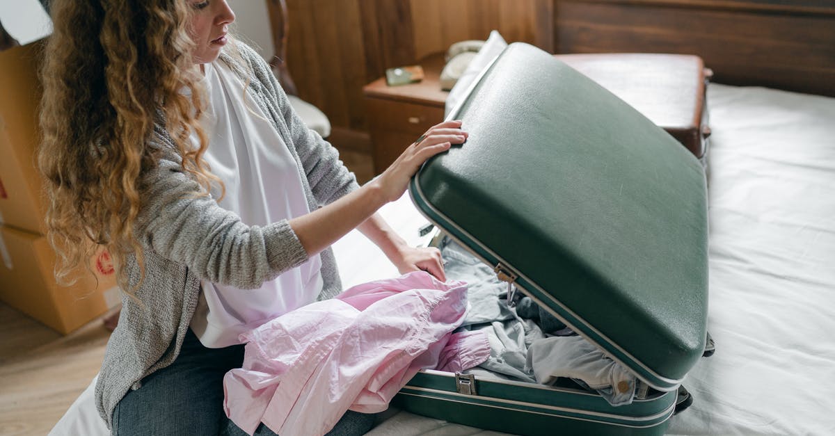 What do I need to prepare for if I am making a trip out of state from New York? - Focus woman packing suitcase on bed What do I need to prepare for if I am making a trip out of state from New York? - Focus woman packing suitcase on bed