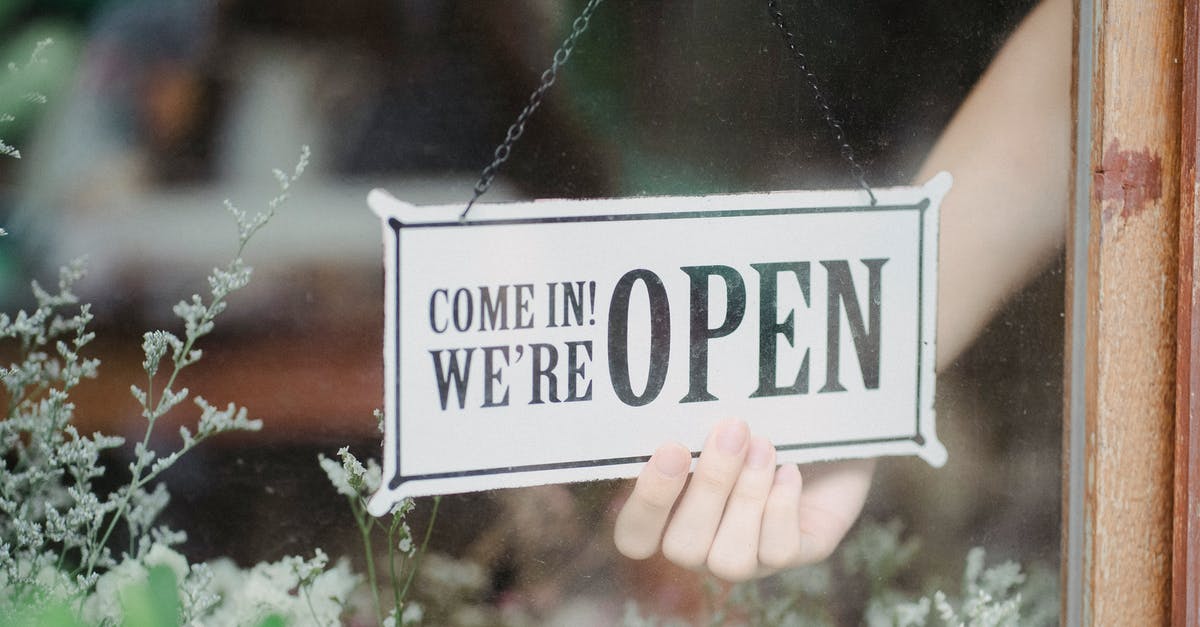 What do shops mean when they are open 7/7? - Crop anonymous person flipping signboard on window of floral shop in modern city What do shops mean when they are open 7/7? - Crop anonymous person flipping signboard on window of floral shop in modern city