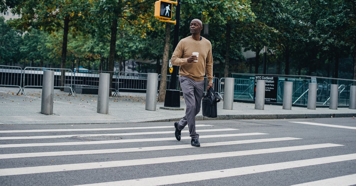 What does amber - green traffic light mean in South Korea? - Full body of African American male walking on pedestrian crossing on asphalt road with cup of hot drink and briefcase What does amber - green traffic light mean in South Korea? - Full body of African American male walking on pedestrian crossing on asphalt road with cup of hot drink and briefcase