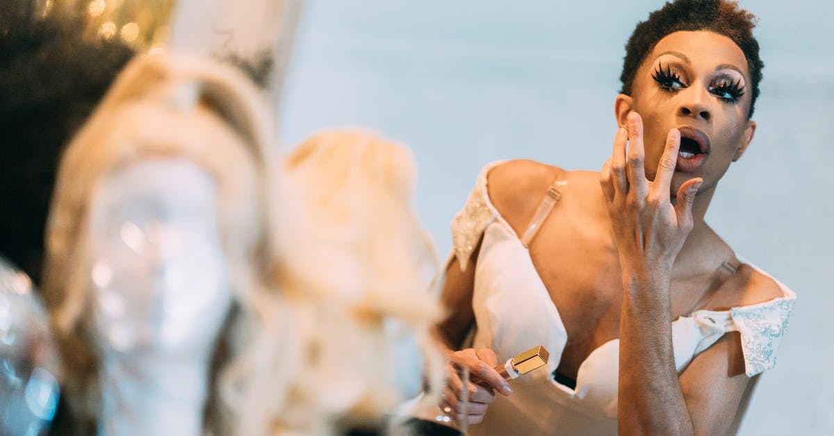 What does the appeals process look like if you are denied entry to the United States? - Ethnic man applying lipstick in front of mirror