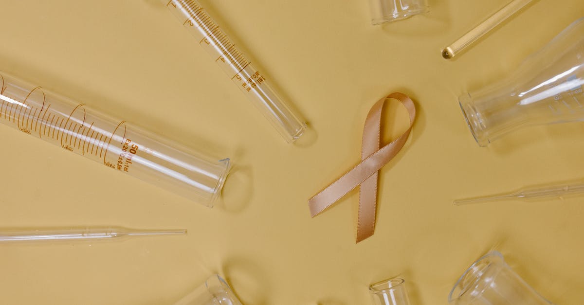 What does the Free Recovery sign (UK) actually mean? - Top view of pink ribbon representing cancer placed on yellow background among glass test tubes and flasks in light studio What does the Free Recovery sign (UK) actually mean? - Top view of pink ribbon representing cancer placed on yellow background among glass test tubes and flasks in light studio