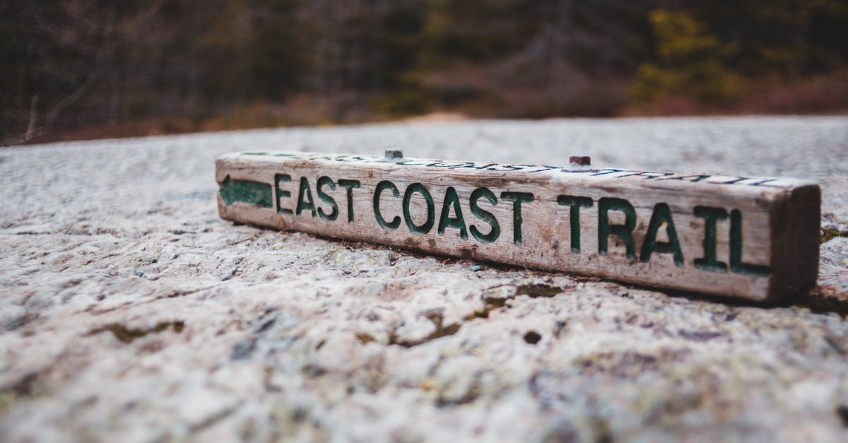 What does this sign on a hiking trail communicate? [closed] - Ground level of wooden direction sign with east coast trail inscription placed on road near forest