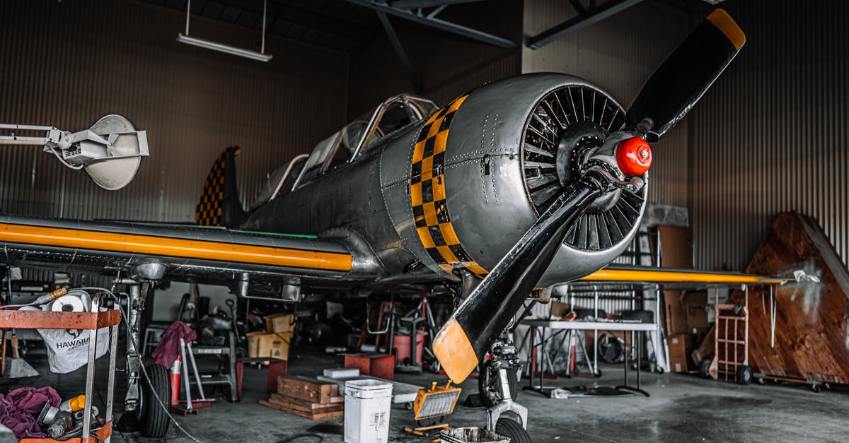 What facilities does Ottawa airport provide after security? - Old fashioned gray propeller jet parked for maintenance in modern spacious air shed What facilities does Ottawa airport provide after security? - Old fashioned gray propeller jet parked for maintenance in modern spacious air shed