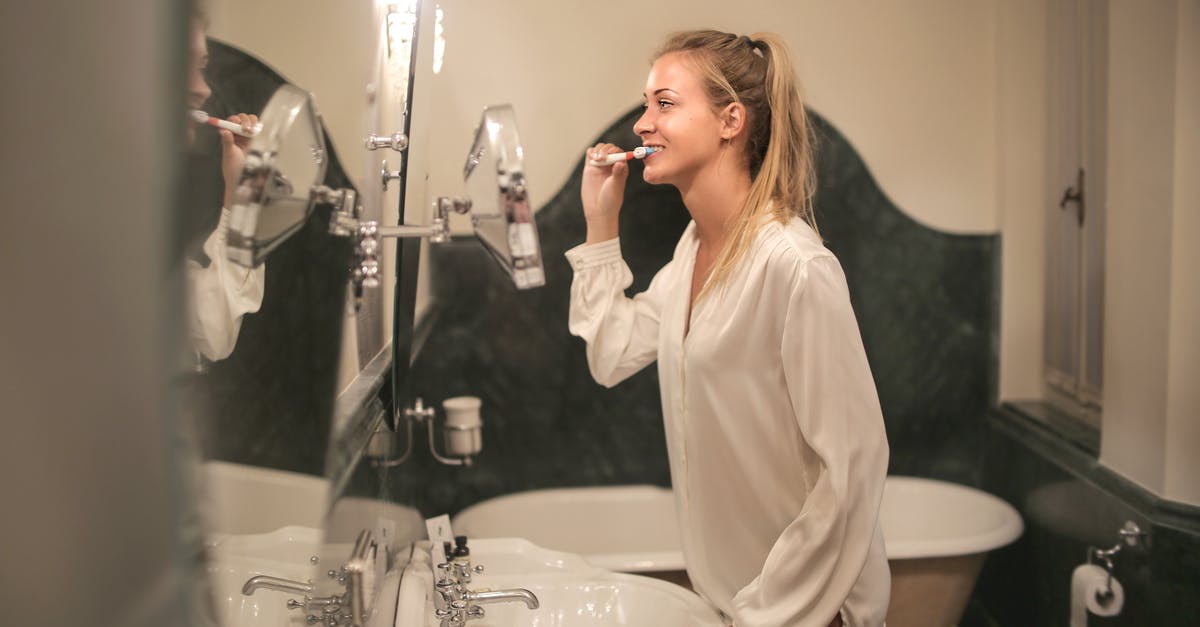 What happens to the unfinished open soaps in hotel bathrooms? - Young woman cleaning teeth in bathroom