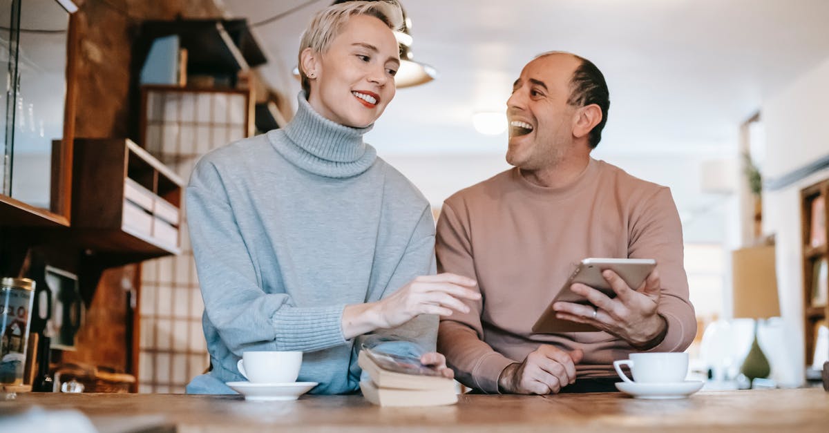 What if I miss a connection and don't have money to book next flight? - Delighted adult ethnic man laughing and looking at wife while watching together funny video on tablet and drinking coffee in sunny morning at home What if I miss a connection and don't have money to book next flight? - Delighted adult ethnic man laughing and looking at wife while watching together funny video on tablet and drinking coffee in sunny morning at home