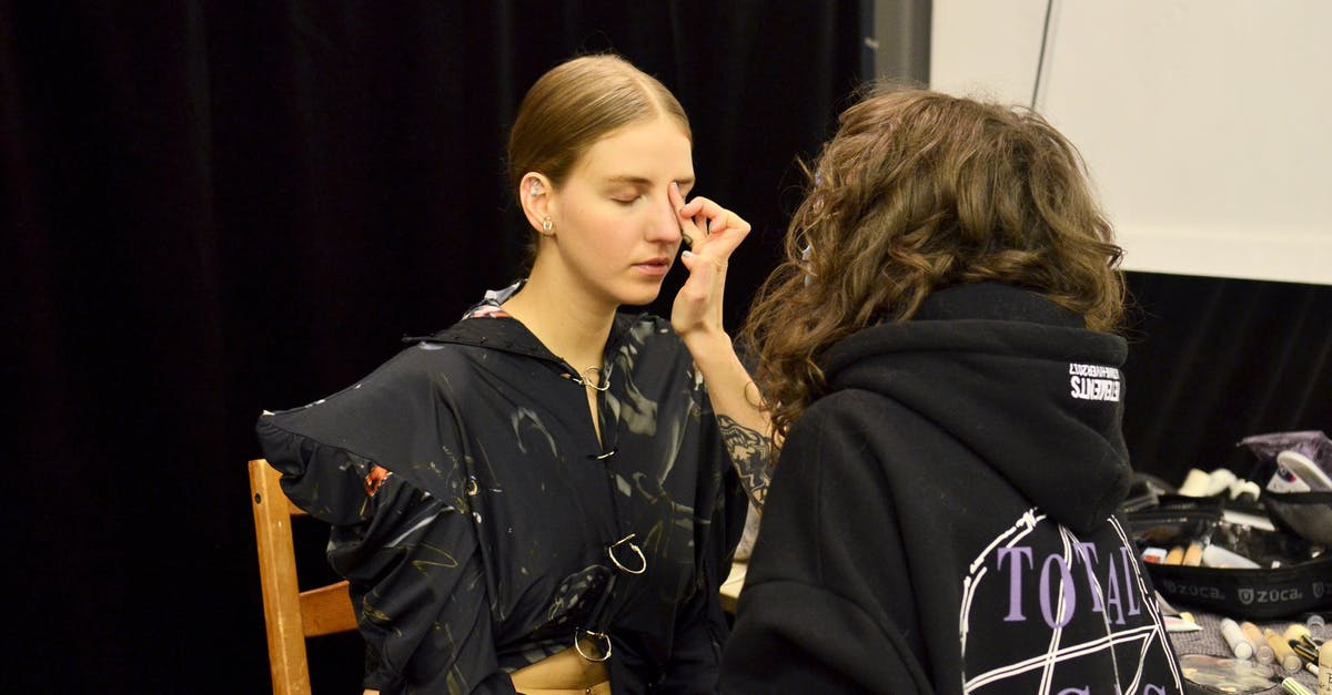 What is correct when applying for a visa: VFS or Embassy guidelines? - Female stylist applying foundation on face of model during preparation for photo session
