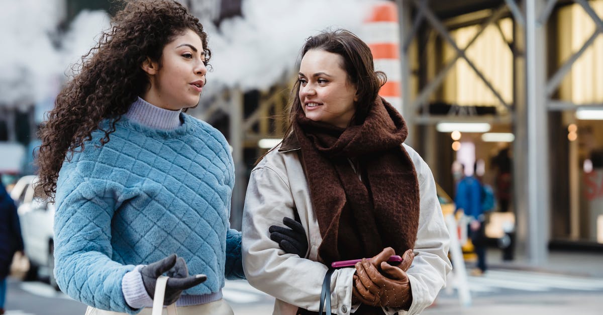 What is the best way to get Baht in Thailand? - Positive stylish multiethnic women talking and crossing road in city What is the best way to get Baht in Thailand? - Positive stylish multiethnic women talking and crossing road in city