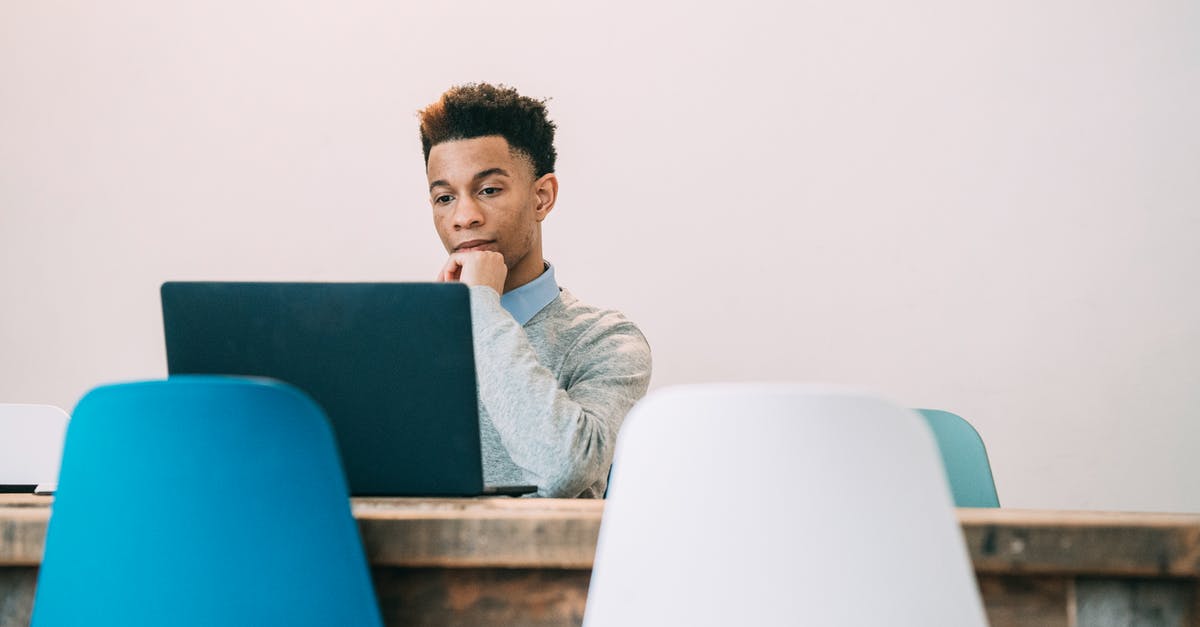 What is the correct visa type to attend a conference in Vietnam? - Pensive ambitious African American male touching chin and using netbook at table of modern office on white background