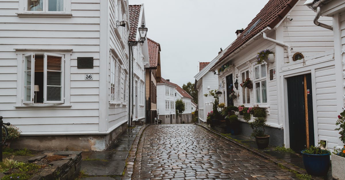 What is the highest altitude town or village with accommodation in Cambodia? - Narrow paved walkway on street between small residential buildings after raining in overcast weather What is the highest altitude town or village with accommodation in Cambodia? - Narrow paved walkway on street between small residential buildings after raining in overcast weather