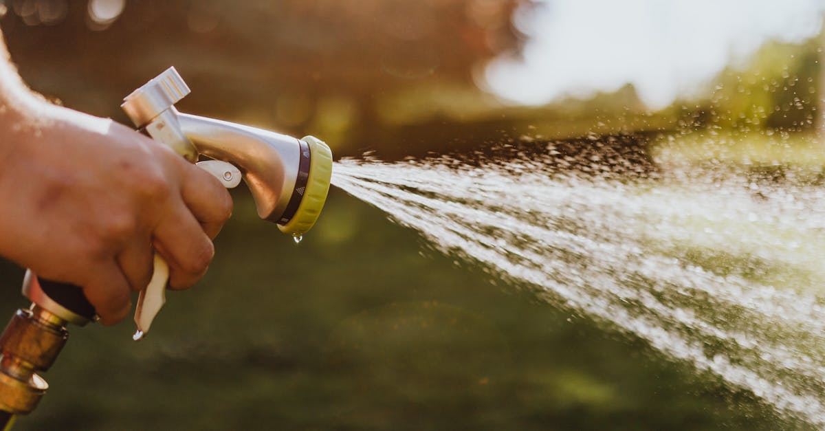 What is the intended use of the water hose in Indian restrooms? [duplicate] - Selective Focus Photo of a Person Using a Spray Hose